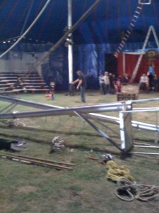 Here is the inside of the tent, with rehearsals going on before everything got finished.  That is the high wire platform in the foreground with the other pole crossing it.  Notice that the feet are already in position, the poles will be lifted, pivoting on their feet.